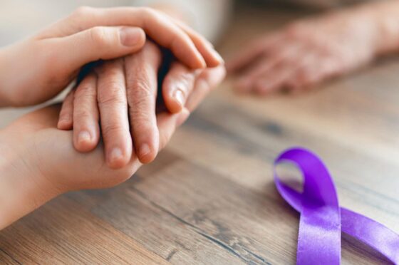 Hands beside purple cancer awareness ribbon