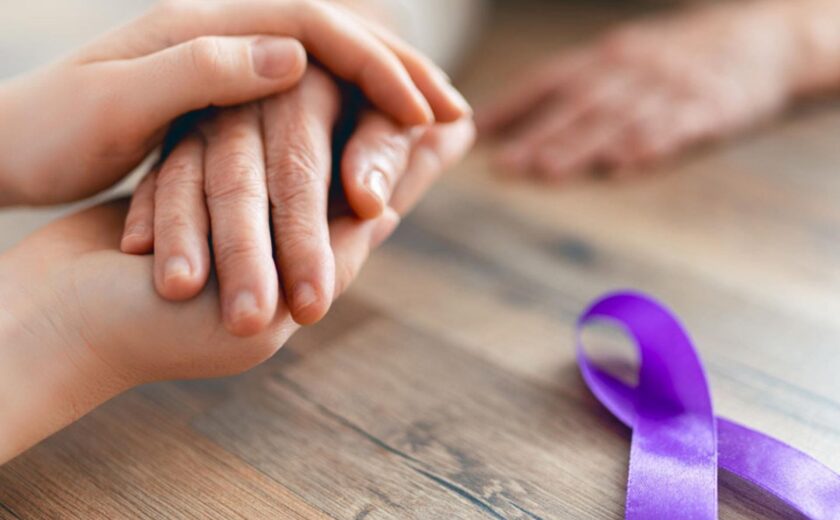Hands beside purple cancer awareness ribbon