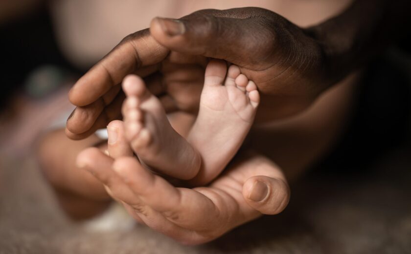 Hands cradling newborn baby's feet