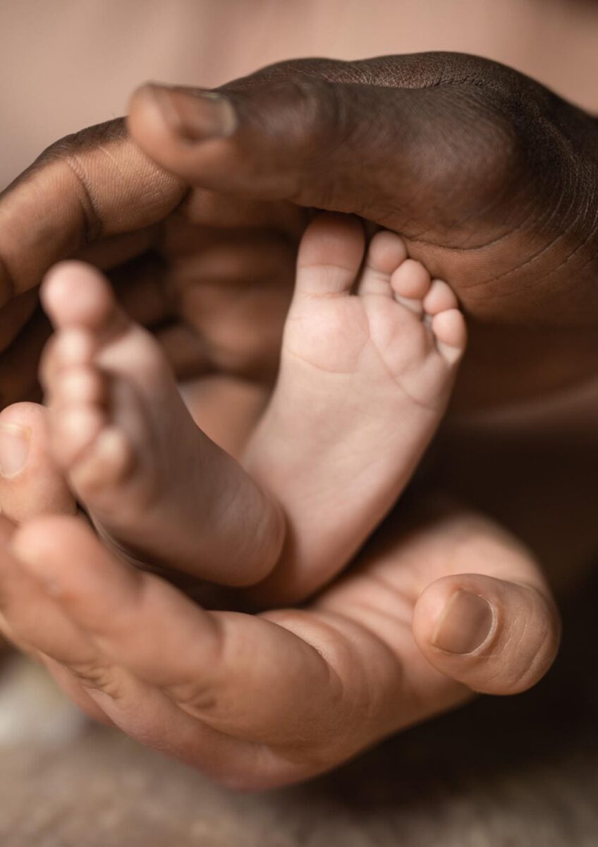 Hands cradling newborn baby's feet
