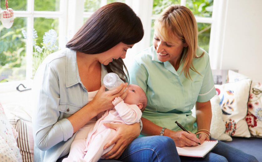 Health visitor supporting mother and newborn at home