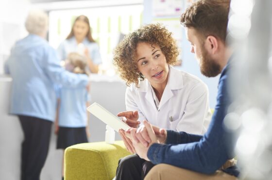 Healthcare professional speaking with patient in clinic waiting area