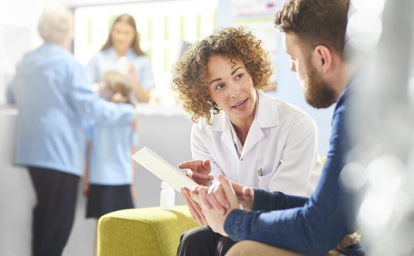 Healthcare professional speaking with patient in clinic waiting area