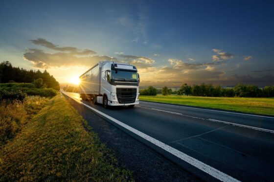 HGV driving along road at sunset