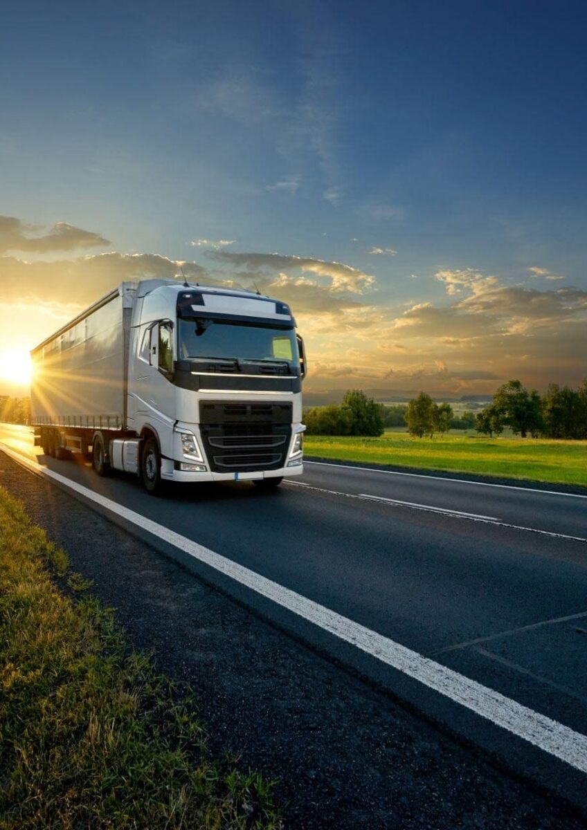 HGV driving along road at sunset