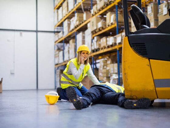 Injured warehouse worker beside forklift