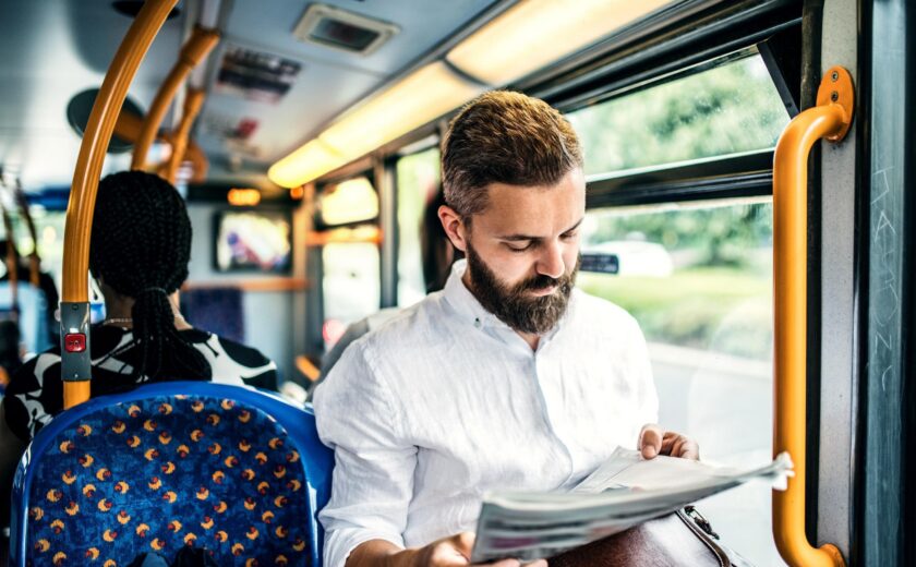 Man reading newspaper on bus