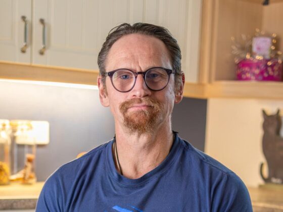 Ian Westmoreland with glasses seated in kitchen