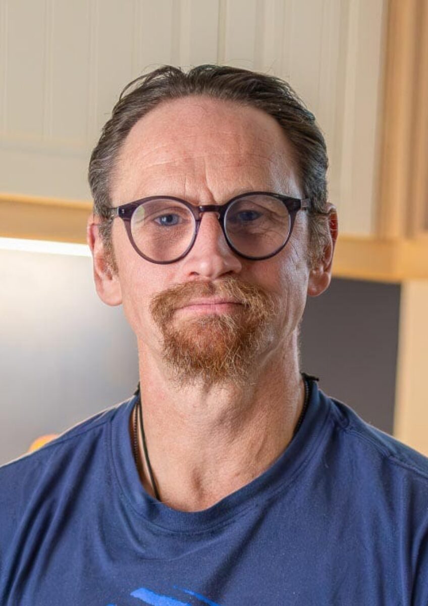 Ian Westmoreland with glasses seated in kitchen