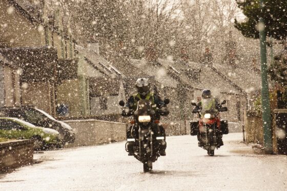 Motorcyclists riding through snow