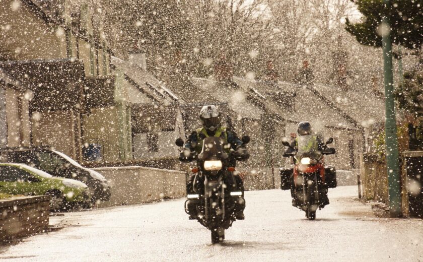 Motorcyclists riding through snow