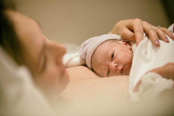 Newborn baby resting against parent