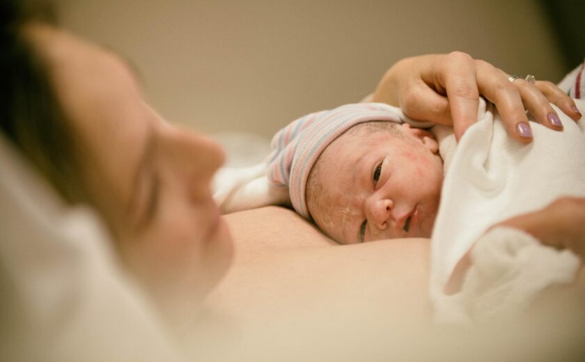 Newborn baby resting against parent