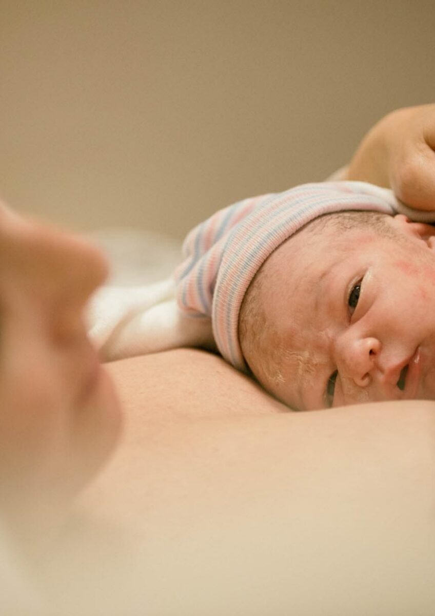 Newborn baby resting against parent