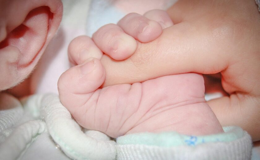 Newborn holding adult finger