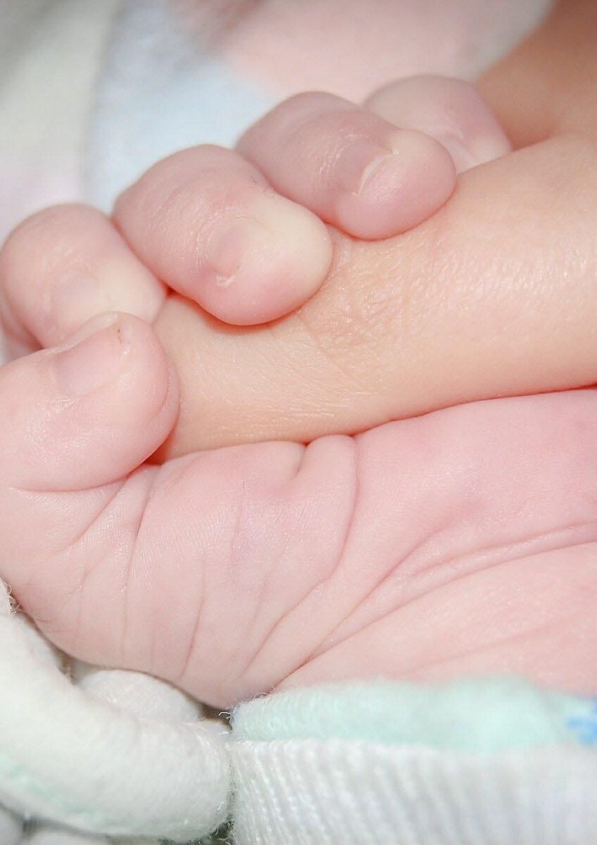 Newborn holding adult finger