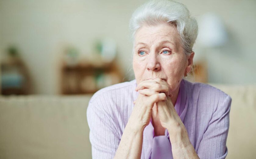 Older woman sitting thoughtfully at home