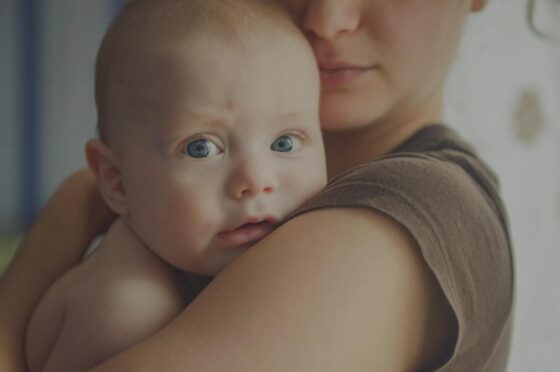 Parent holding baby against shoulder