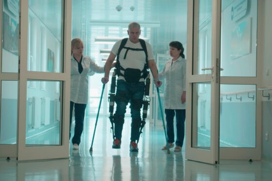 Patient using exoskeleton with clinicians in hospital