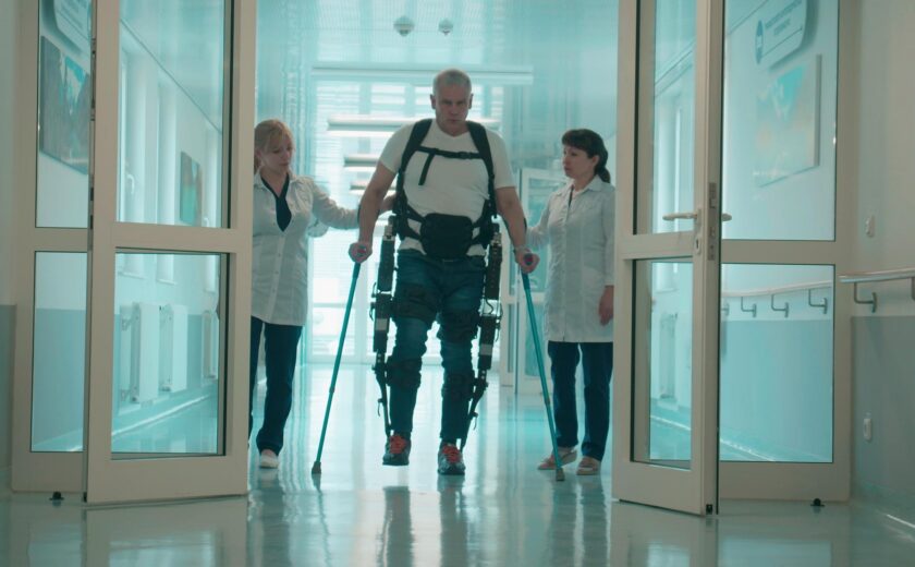 Patient using exoskeleton with clinicians in hospital
