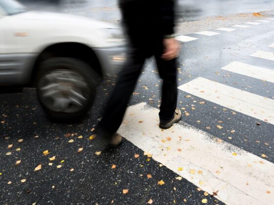 Pedestrian crossing road near passing car