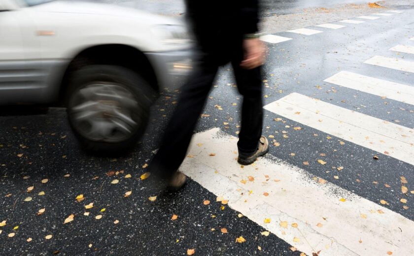Pedestrian crossing road near passing car