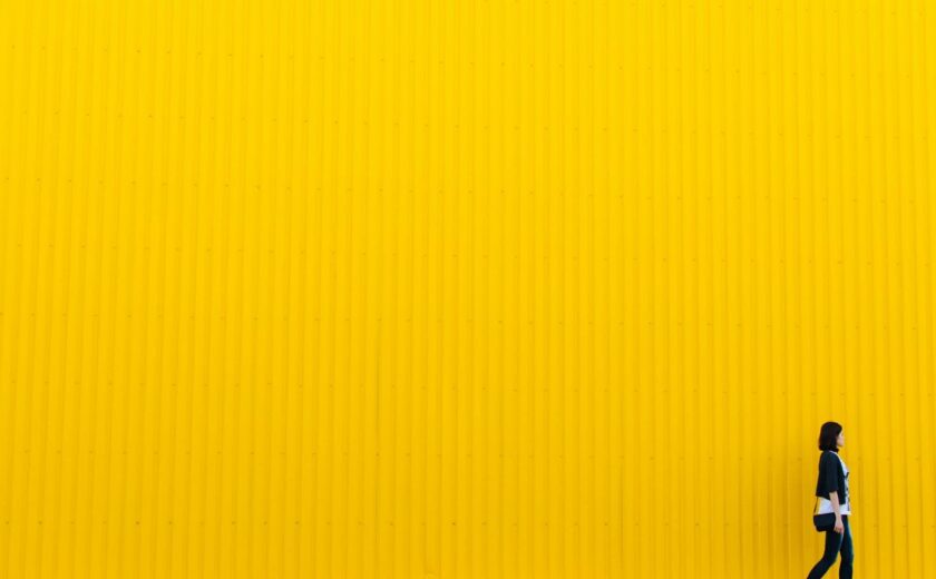 Person walking beside bright yellow wall