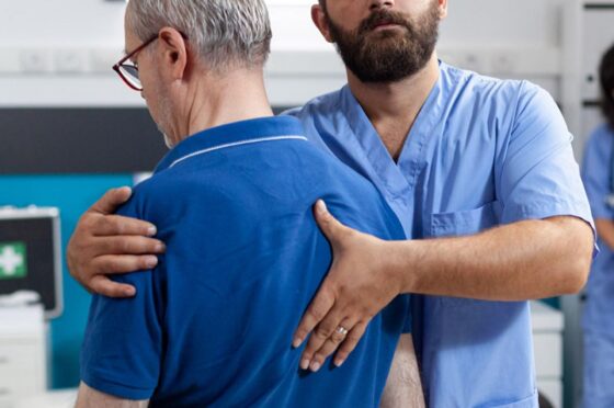 Physiotherapist supporting older man during shoulder assessment