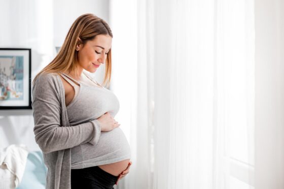 Pregnant woman holding her bump at home
