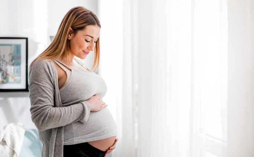 Pregnant woman holding her bump at home