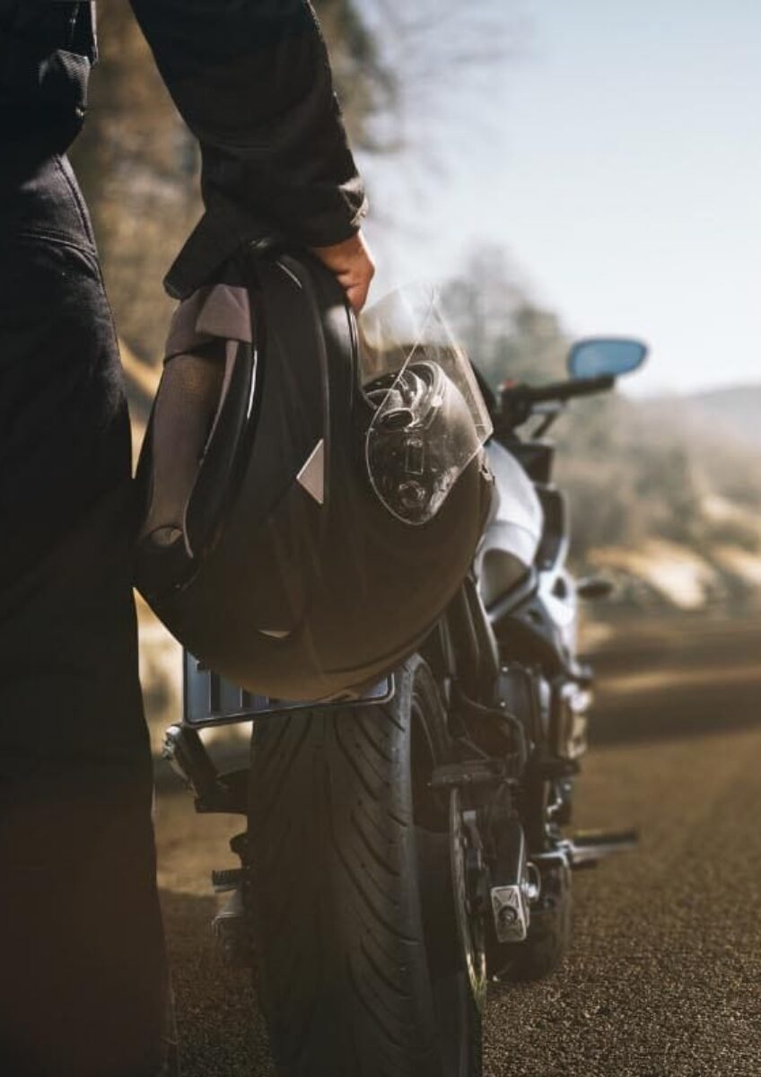 Rider holding helmet beside motorcycle