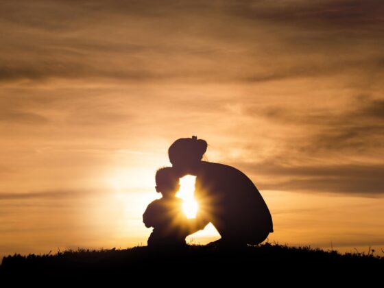 Silhouette of child and adult at sunset