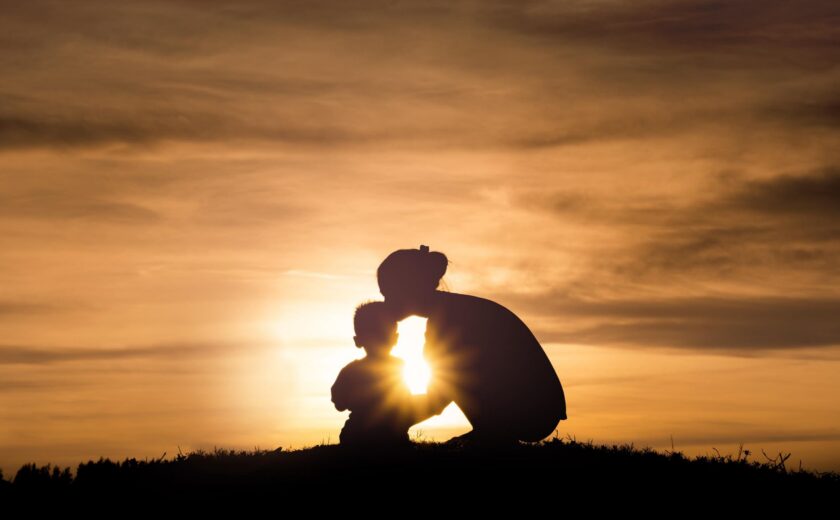 Silhouette of child and adult at sunset