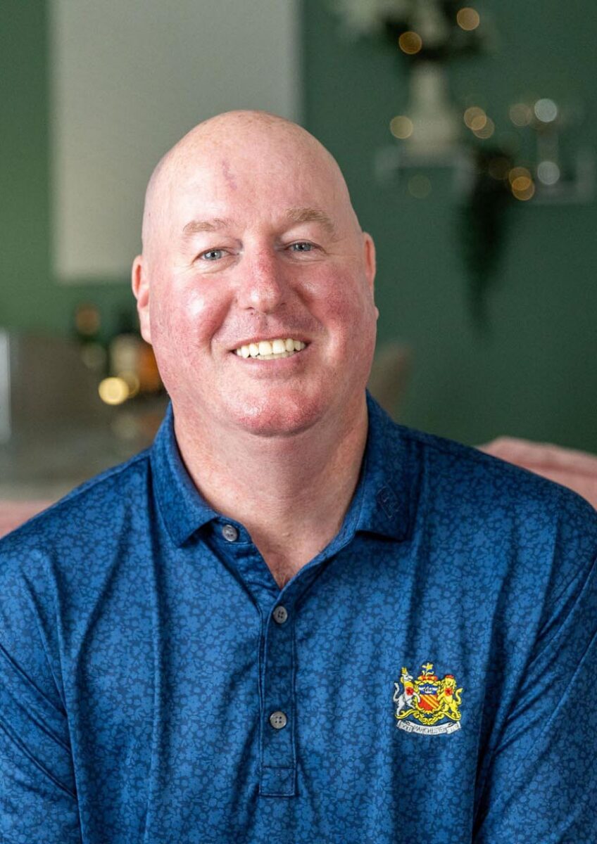 Smiling man seated at home wearing blue polo shirt