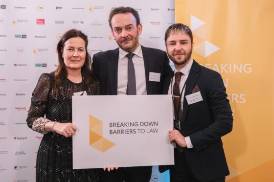 Three colleagues holding award at Breaking Down Barriers event