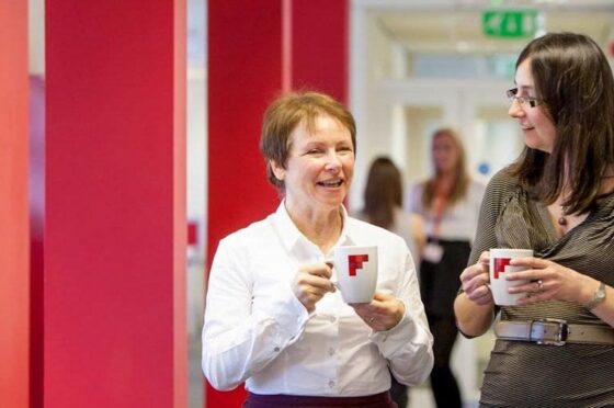 Two colleagues talking with mugs in office