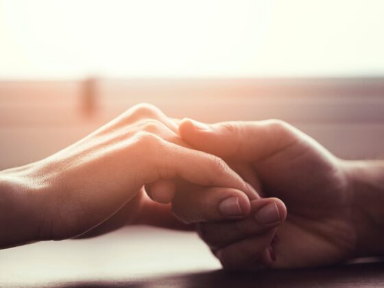 Two people holding hands in warm light
