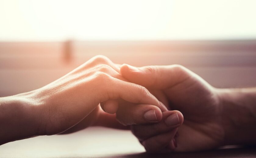 Two people holding hands in warm light