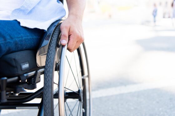 Wheelchair user holding wheel outdoors