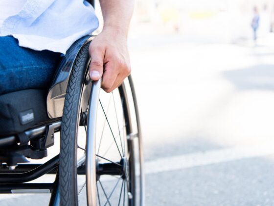 Wheelchair user holding wheel outdoors