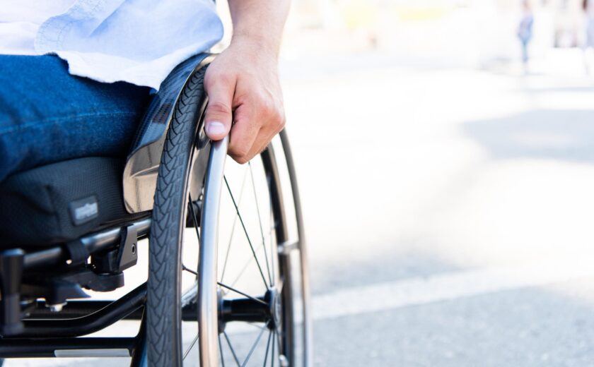 Wheelchair user holding wheel outdoors