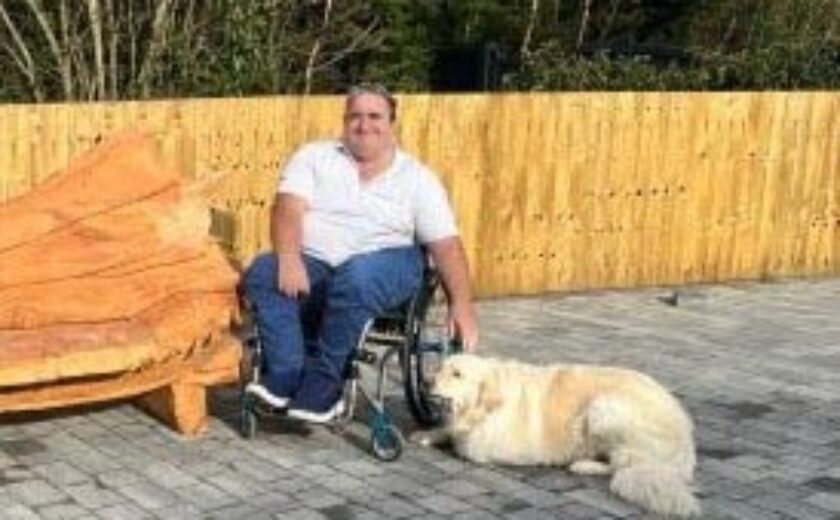 Wheelchair user seated with guide dog in garden