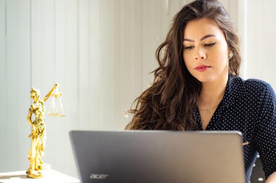 Woman using laptop beside legal scales