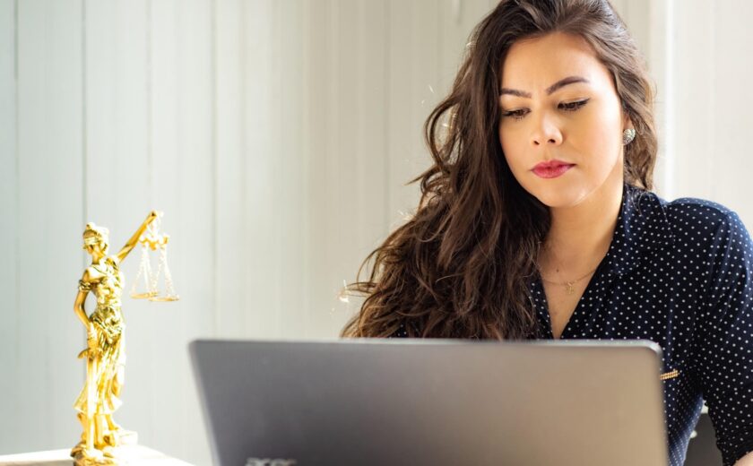 Woman using laptop beside legal scales