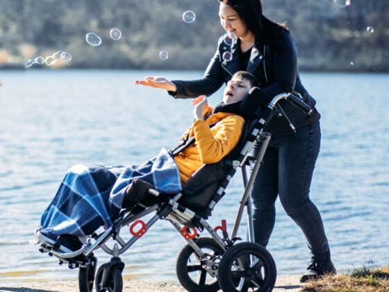 Woman walking with child in adaptive buggy by lake