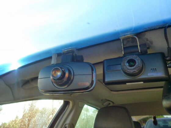 Two dash cameras mounted inside a vehicle on the front windshield