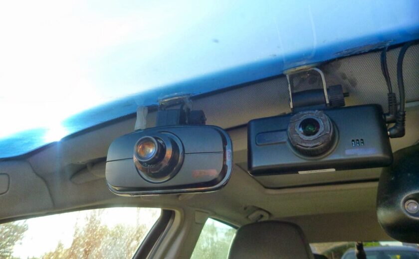 Two dash cameras mounted inside a vehicle on the front windshield