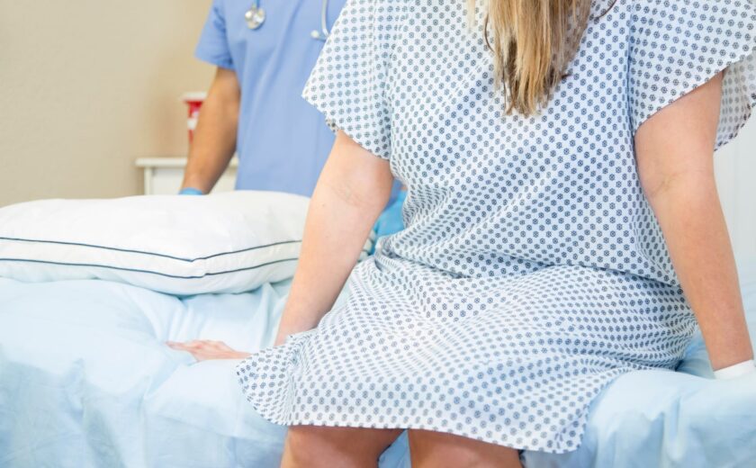 Patient sitting on hospital bed with medical staff in background