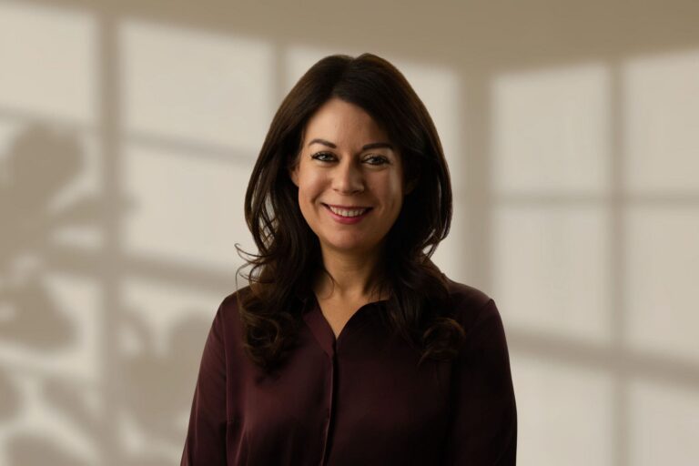 Woman with dark hair smiling against a softly lit background