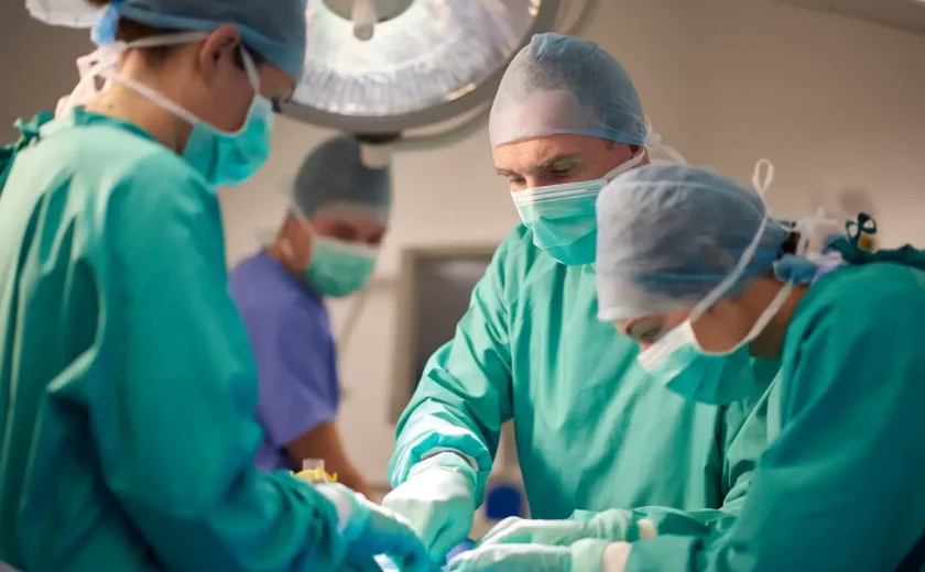 Surgical team dressed in scrubs and masks performing operation in operating theatre